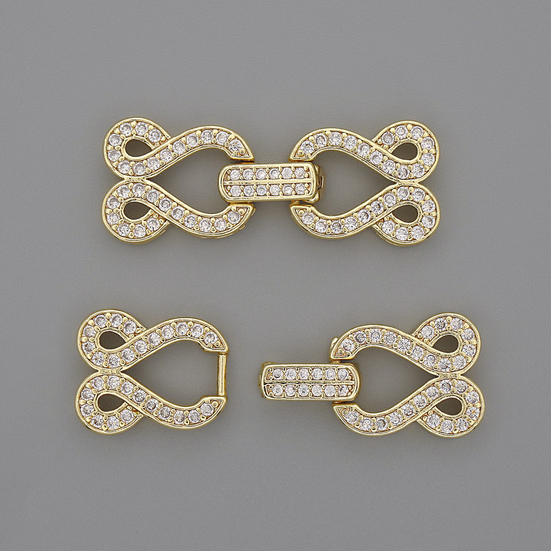 Kovové zapínání na dvě nitě s bílými štrasovými kamínky, průměr 30×12 mm, zlatavá barva kovu