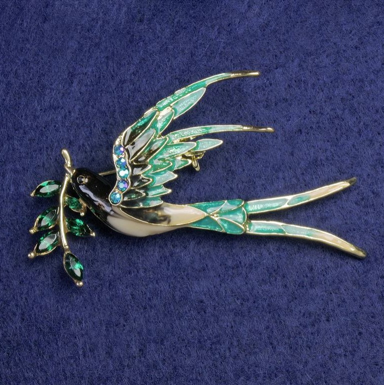 Brož Vlaštovka se větvičkou béžová a zelená smalt, zelené krystaly, modré štrasové kamínky, zlatý kov 62×48 mm