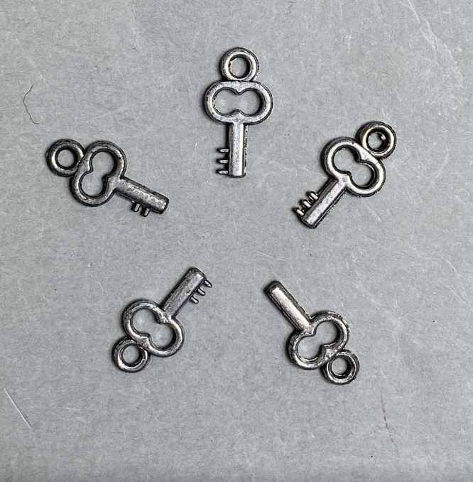 SLEVA! Balení 0,5 kg Přívěšek ve tvaru klíče z plastu, barva tmavě stříbrná, rozměry 20×11×3 mm ± otvor, průměr 3 mm